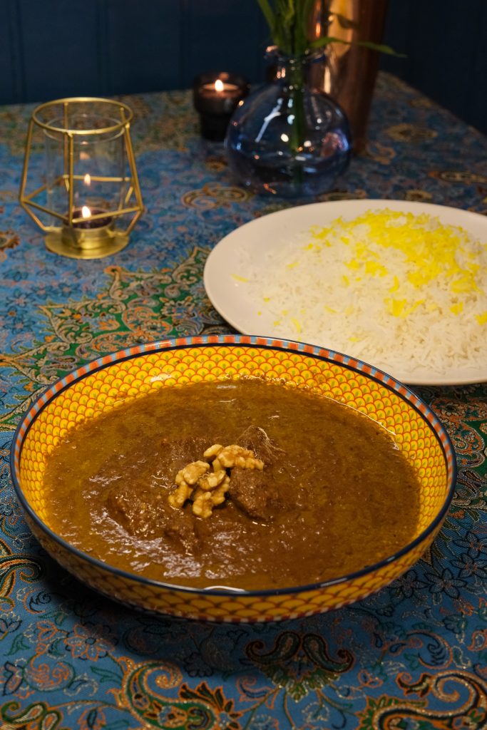 Fesenjan persa tradicional con nueces y granada servido con arroz en restaurante persa en Madrid.